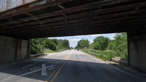 POV:-Truck-driving-underneath-bridge-with-a-cargo-train-passing-on-the-rails-above-the-road