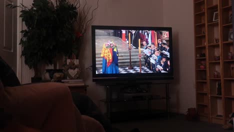 Man-sitting-to-watch-Her-Majesty-Queen-Elizabeth-ceremonial-funeral-service-broadcast-on-British-television-at-home