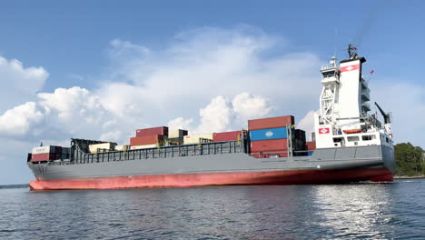 Large-cargo-ship-with-containers-filmed-from-a-boat-passing-by-on-the-side