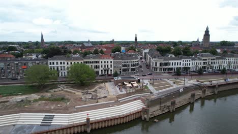 Sideways-ascending-aerial-movement-showing-the-quay-under-construction-at-river-IJssel-with-work-in-progress-on-the-IJsselkade-boulevard-of-tower-town-Zutphen-urban-development