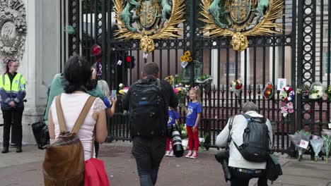 September-12-2022:-Mother-With-Her-Three-Young-Girls-Wearing-Blue-T-Shirt-And-Holding-Floral-Bouquet-Outside-Buckingham-Palace-Gates-For-Queen-Elizabeth-And-Press-Taking-Photos-Of-Them