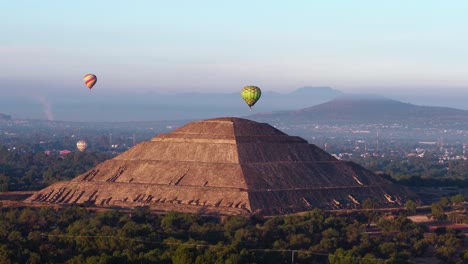 Hot-air-balloons-and-the-pyramid-of-the-sun,-during-sunset-in-Teotihuacan,-Mexico---orbit,-drone-shot