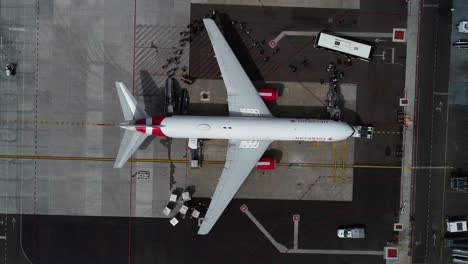 Aerial-view-of-passengers-walking-in-to-a-airplane-at-a-airport-terminal---top-down,-drone-shot