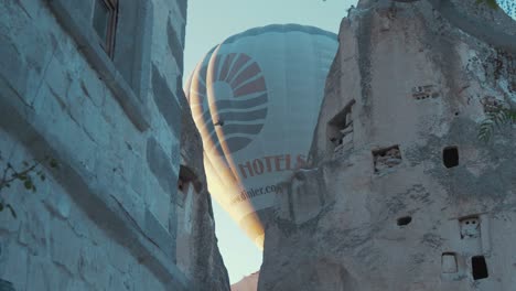 Hot-air-balloon-passes-over-cave-dwellings-Goreme,-Cappadocia