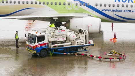 An-employee-of-the-ground-service-of-the-airport-operating-the-tanker-refills-the-aircraft-with-aviation-fuel-on-rainy-days-in-Bangkok