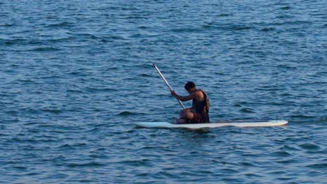 Hispanic-boy-sitting-on-surfing-board-and-rowing-on-lago-Paranoa