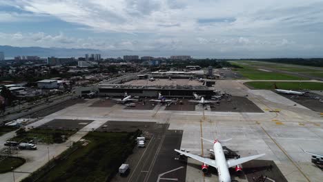 Aerial-view-towards-planes-at-a-airport-terminal-in-sunny-Puerto-Vallarta,-Mexico