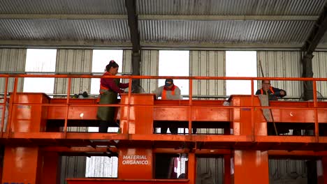Slow-motion-pan-left-to-right-of-workers-sorting-waste-on-a-conveyor-belt