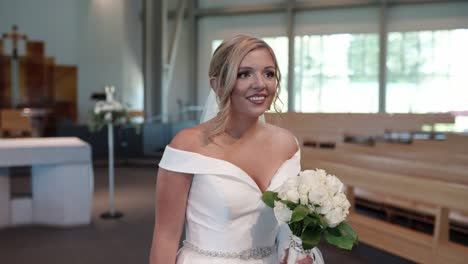 Bride-walking-down-the-aisle-in-a-white-wedding-dress-holding-a-white-rose-bouquet