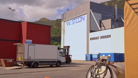 Filmische-Logo-Enthüllung-Von-Westcon-Yards-In-Olensvag,-Norwegen---Werft-Firmenlogo-Auf-Dem-Gebäude,-Das-Hinter-Der-Elektrischen-Ausrüstung-Im-Verschwommenen-Vordergrund-Zu-Sehen-Ist