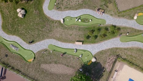 People-playing-mini-golf-at-the-same-time,-in-different-holes