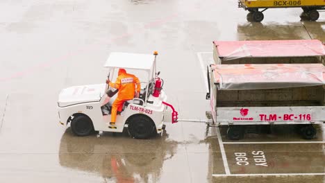 Luggage-carts-from-Lion-Air,-a-low-cost-airline-on-the-airfield-at-Don-Mueang-International-airport-in-Bangkok,-Thailand