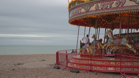 People-enjoy-riding-old-fashioned-horse-carousel-on-Brighton-Beach,-UK