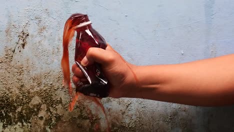 hand-squeeze-the-bottle-filled-with-red-liquid-until-it-spurts-in-slow-motion