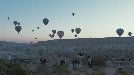 Tourists-walking-along-path-towards-Cappadocia-hot-air-balloons