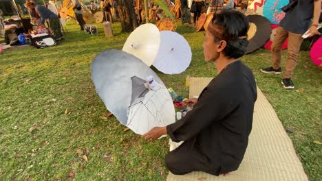 Umbrella-painting-artist,-who-is-painting-his-work-at-the-Indonesian-Umbrella-Festival