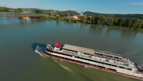 Toma-En-órbita-Fpv-Del-Ferry-Que-Cruza-El-Puente-Mauterner,-Río-Danubio-En-Weissenkirchen,-Austria
