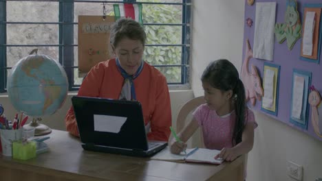 Slowmotion-shot-of-a-teacher-educating-a-young-school-girl-at-the-desk