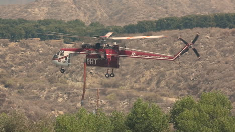Firefighting-helicopter-approaching-a-pond-ready-to-refill-water,-California-Wildfires