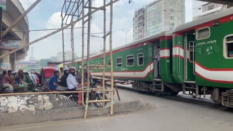 Einheimische-Warten-Darauf,-Dass-Der-Intercity-Zug-In-Der-Dhaka-Unterführung-In-Bangladesch-Vorbeifährt,-Bevor-Sie-Die-Straße-überqueren-Können