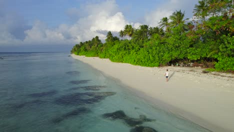 Vista-Aérea-Estática-Del-Hombre-Caminando-Pacíficamente-Por-La-Playa-Tropical-En-Maldivas-Al-Amanecer