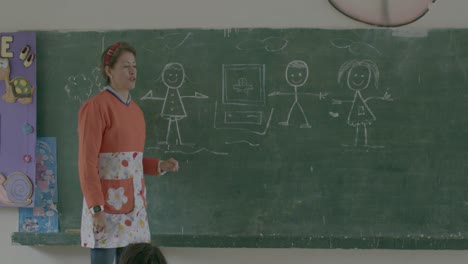 Slowmotion-shot-of-a-teacher-speaking-in-front-of-her-class-beside-a-chalkboard