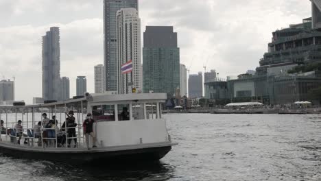 llandscape-view-of-passenger-ferry-boat-in-chaophraya-river-with-skyscraper-hotel-building-on-the-river-bank