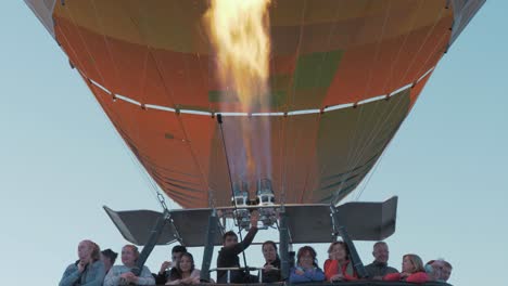 Excited-group-flying-in-hot-air-balloon-while-aeronaut-operates-balloon