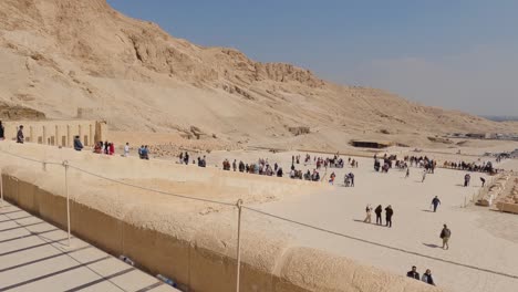 Toma-Panorámica-Desde-La-Parte-Superior-Del-Templo-Mortuorio-De-Hatshepsut-Mirando-Hacia-Los-Turistas-Que-Exploran-El-Sitio-En-Luxor,-Egipto