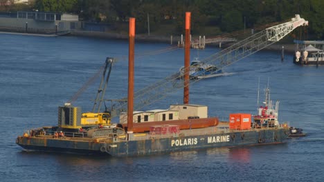 Crawler-crane-and-other-building-materials-are-shipped-up-the-river-on-a-barge