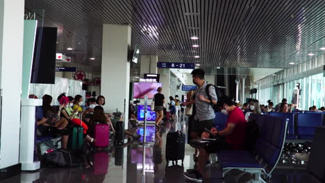 Pan-right-shot-of-people-with-face-masks-waiting-in-lobby-of-Saigon-Airport,-Vietnam