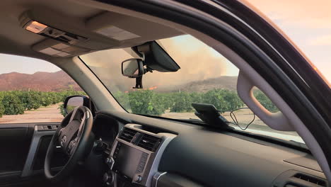 Inside-view-of-Parked-Car-to-The-Outside-Revealing-a-Camera-With-Fire-in-the-Background