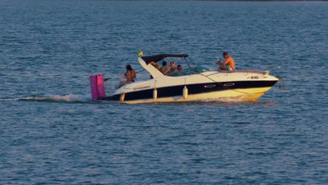 Group-of-friends-having-fun-on-a-boat-trip-on-lake,-golden-hour-in-slow-motion