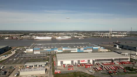 Drone-view-of-industrial-estate-in-Dartford-with-view-on-amazon-and-Europa-warehouses-and-queen-Elizabeth-II-bridge-over-river-and-commercial-ships-in-background