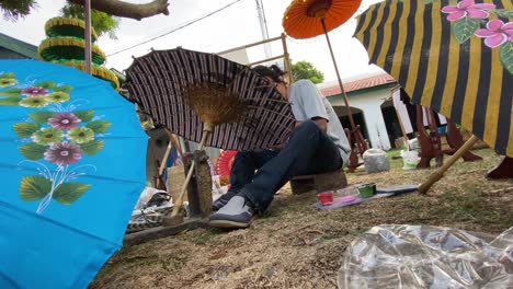 Umbrella-painting-artist,-who-is-painting-his-work-at-the-Indonesian-Umbrella-Festival