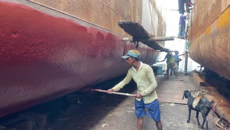 Young-worker-boy-painting-ship-hull-at-a-dry-dock-shipyard-in-Dhaka,-Bangladesh