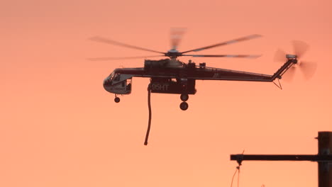 Helicopter-Sikorsky-CH-54-Tarhe-N795HT,-S-64-Firefighting-Skycrane-flying-against-pink-color-sunset-sky-on-a-mission-to-put-out-a-wildfire-in-Hemet---tracking-shot