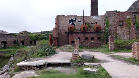 Panning-across-neglected-Porth-Wen-industrial-rusty-brickwork-boiler-and-furnace-ruins-on-Anglesey-coast