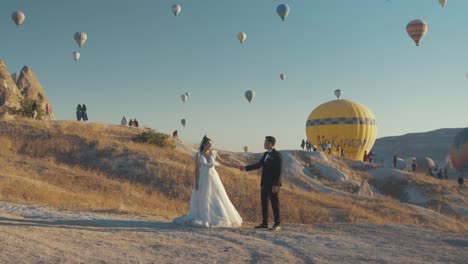 Bride-and-Groom-taking-photos-against-Cappadocia-Hot-air-balloon-backdrop