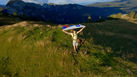 fpv-footage-was-filmed-in-the-Slovenian-mountain-village-in-the-alps-with-a-drone-flying-fast-over-mountains-filmed-with-a-GoPro-with-incredible-surrounding-landscapes-with-a-hiker-holding-a-flag