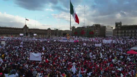 Aerial-view-of-the-Zocalo-Square-crowded-with-people-waiting-for-the-Presidents-Speech,-in-Mexico-city---reverse,-drone-shot
