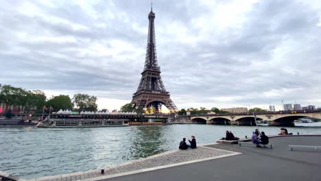 People-Hang-Out-Along-The-Seine-River-With-Eiffel-Tower-And-Pont-d'Iéna-In-Paris,-France