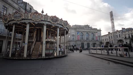 Slowmotion-Rising-Dolly-Shot-Of-A-Carousel-Spinning-In-The-City-Centre-With-Locals-Passing-By