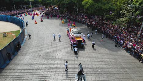Aerial-view-following-a-decorated-truck-at-the-Dia-de-los-Muertos-Parade,-in-sunny-Mexico-city