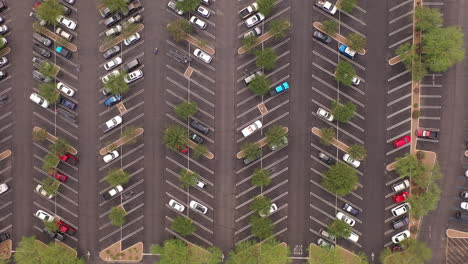 Aerial-view-of-a-large-number-of-cars-of-different-colors-in-a-parking-lot-near-a-shopping-center