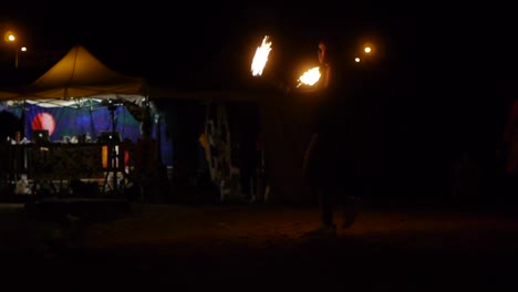 Asian-man-spinning-fire-poi-in-alternate-directions-and-at-rapid-speed-with-movement-and-dance,-filmed-as-full-shot-in-night-time
