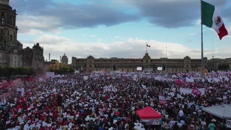 Large-Mexican-flag-waving-at-the-crowded-Zocalo-Square,-in-Mexico-city---Aerial-view