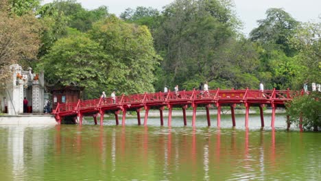 Tourists-on-iconic-red-footbridge-to-cross-Hoan-Kiem-Lake,-Hanoi