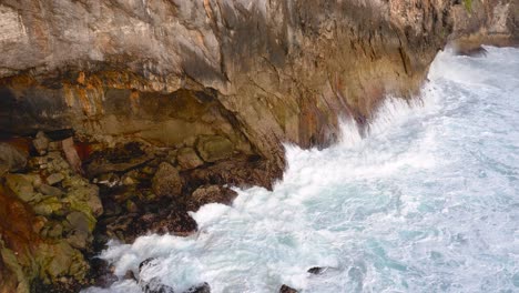 Areal-shot-of-angry-white-waves-crashing-into-the-beautiful-rocky-cliffside-of-Nusa-Penida-Guyangan-Falls