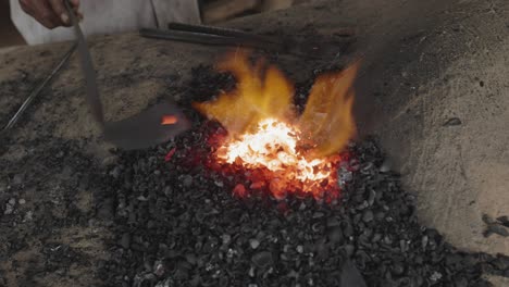 Blacksmith-turns-Red-Hot-Metal-in-Coal-Fire-on-Clay-Furnace